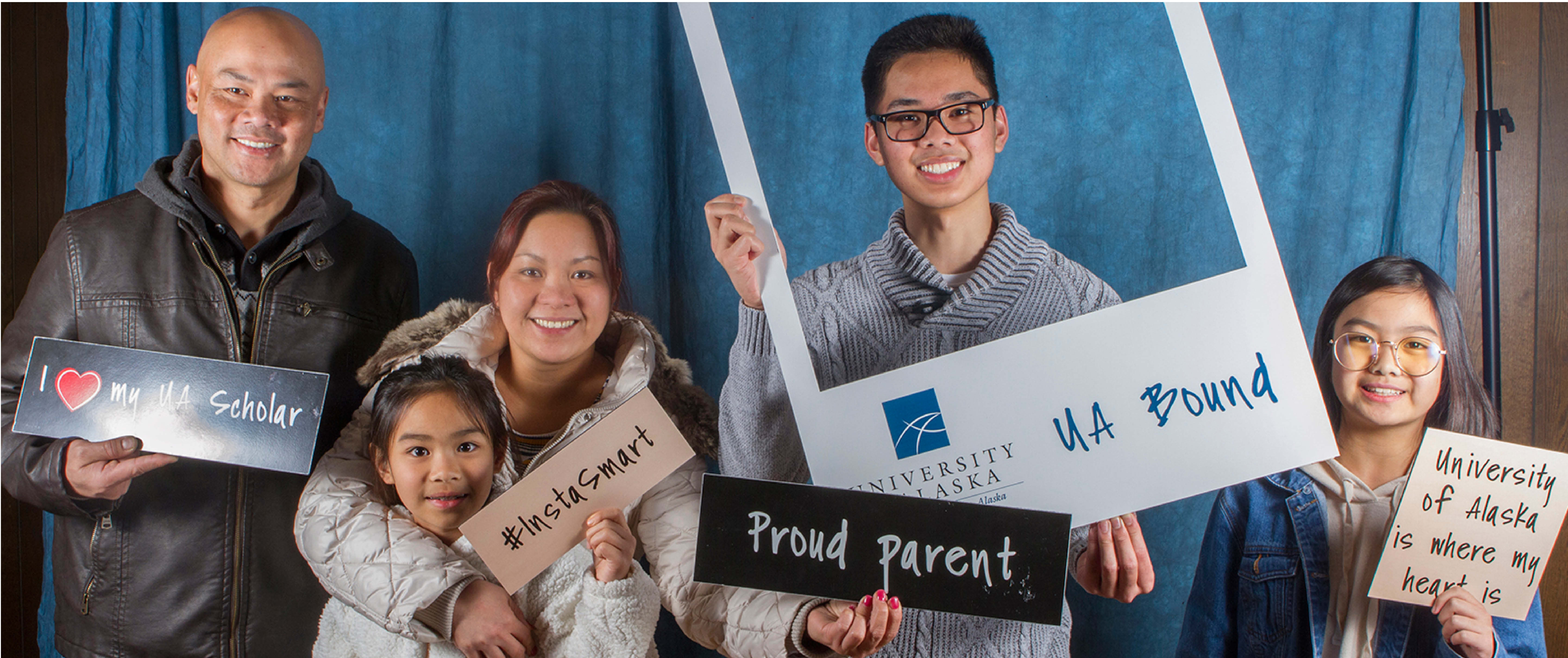 Family standing in photo booth holding signs