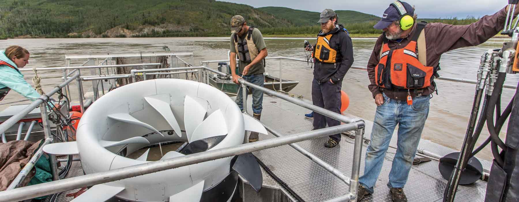 Parker Bradley, a biologist with the Alaska Department of Fish and Game, sets up a net housed under a turbine placed in the Tanana River near Nenana. The work is part of research being carried out by UAF's Alaska Center for Energy and Power (ACEP) to determine the feasibility of hyrokinetic generators being used to help offset the high cost of energy throughout rural Alaska. At far left is UAF fisheries undergraduate student Stephanie Jump who spent the summer of 2015 interning with Fish and Game on the project. At right are ACEP researchers Jeremy Kasper and Jack Schmid.