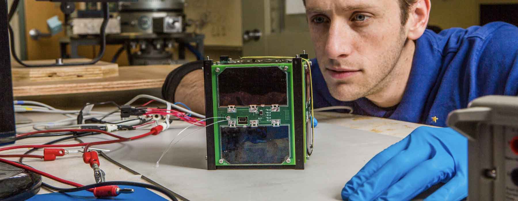 Mechanical engineering major Patrick Wade gives the "cubesat" he helped design and build a final inspection as part of his work with the Alaska Space Grant program. The miniature satellite is scheduled to be launched into space in August, 2015 from Vandenburg Air Force Base in California.