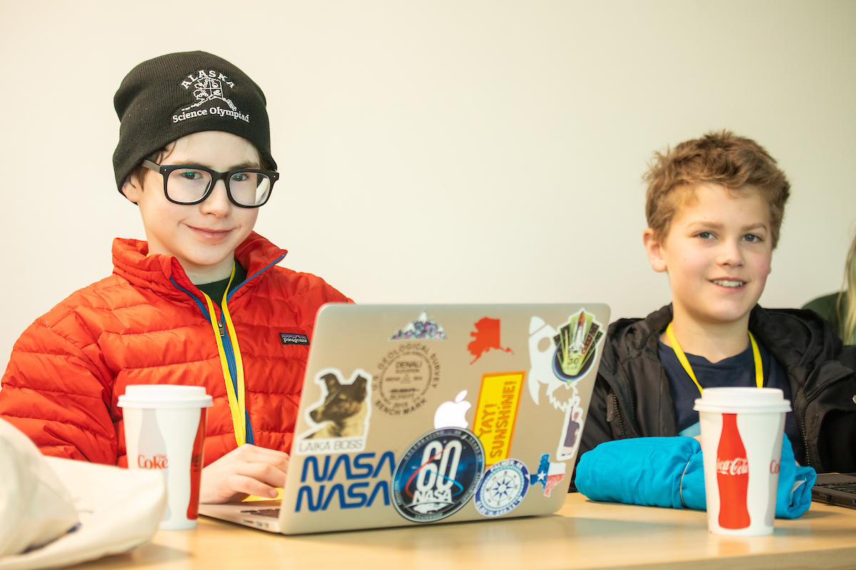 Middle school boys with a laptop covered in science stickers.