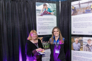 Two people stand in front of a display featuring stories from the For Alaska campaign