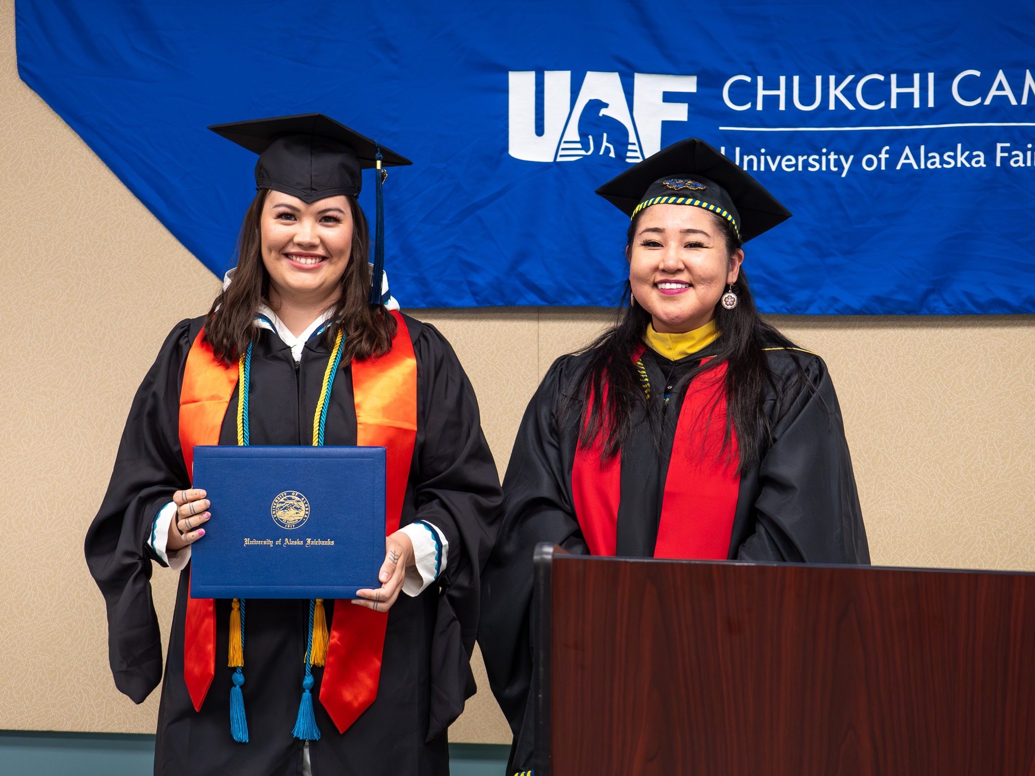 a graduates stands with her diploma at the UAF Chukchi commencement