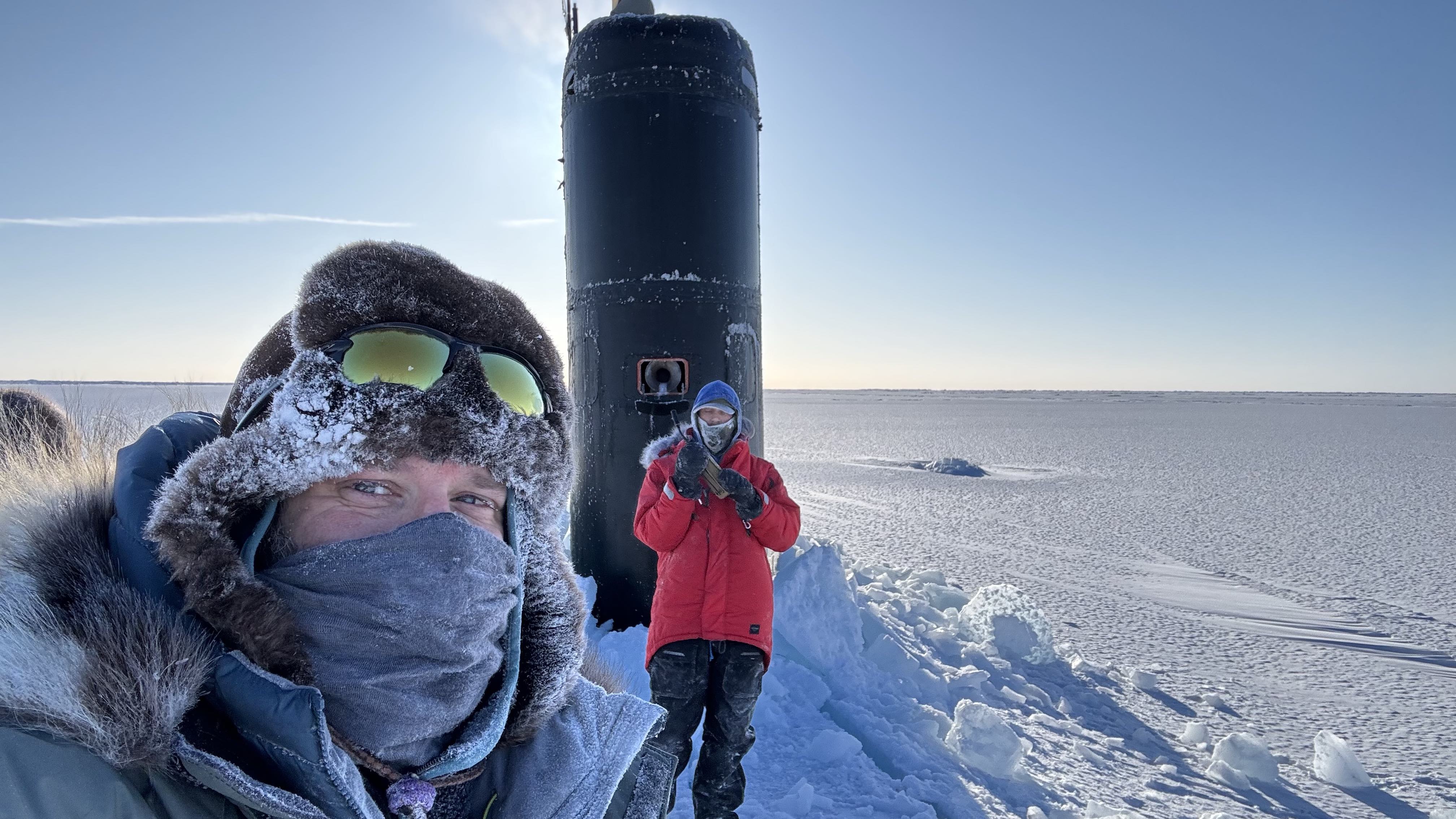 Research professor Andy Mahoney of the University of Alaska Fairbanks Geophysical Institute, left, stands near the USS Hampton’s sail during Operation Ice Camp in March 2024. A civilian employee with the Navy’s Arctic Submarine Lab stands in front of the sail.