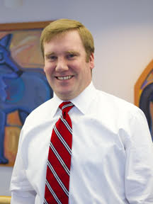 Mat Cooper in a white button up and red tie