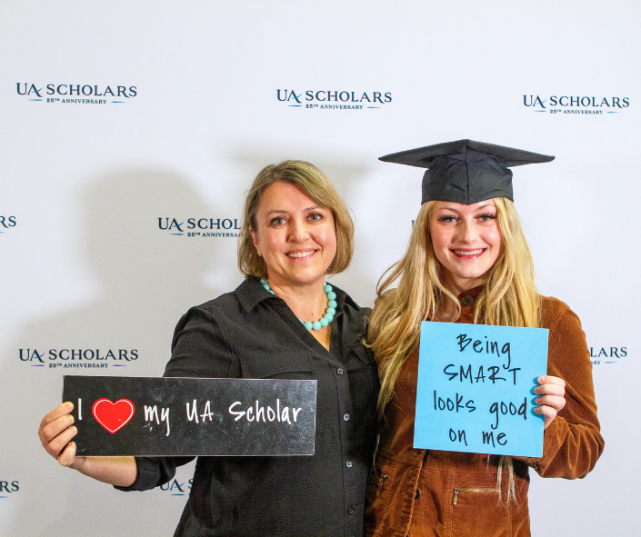 A UA scholar and her mom pose with some signs at the 2023 UAF event photobooth