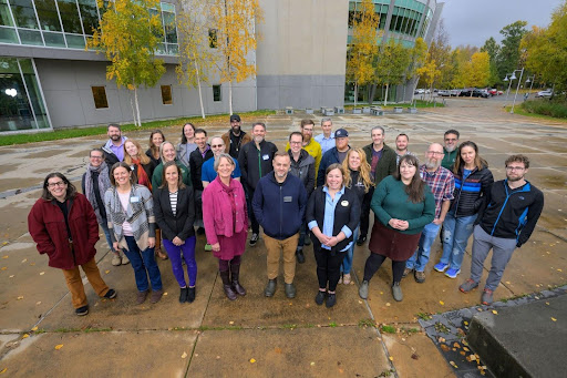 UA faculty group of 20 pose outside the UAS campus in fall