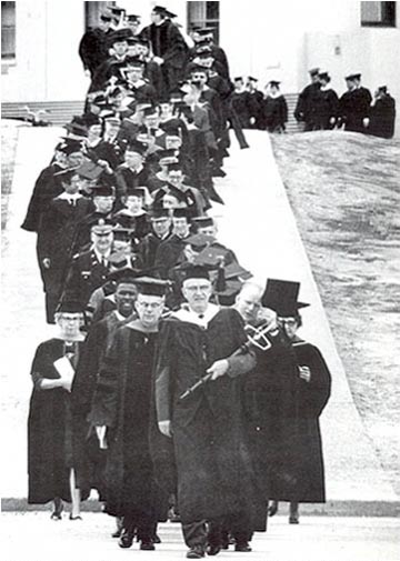 The 1967 commencement parade led by university marshal William Cashen, flanked by Regent Elmer Rasmuson on the left and Dean Earl Beistline on the right. Cashen carried the ceremonial university mace. 