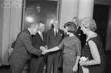 Mrs. Jacqueline Kennedy greets officers of the American Association of Museum Directors as they arrive for tea at the White House. Dr. Froelich Rainey, president, is next in line to shake Mrs. Kennedy's hand. June 5, 1962.